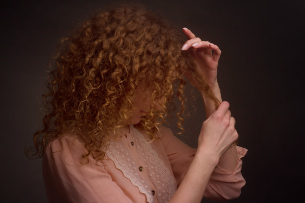 一个卷头发的年轻女子的画室肖像图片下载