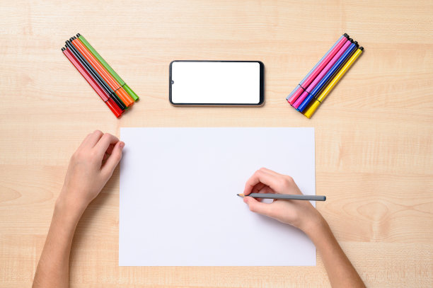 桌上放着一张白色的纸、几支铅笔、一部黑白显示器的电话。那只手躺在纸上拿着一支铅笔。图片下载