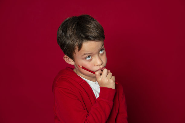 很酷的小男孩用红色的铅笔在红色的背景图片下载