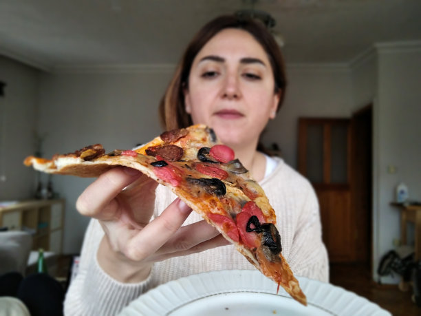 在流行期间在家工作的妇女吃披萨图片下载