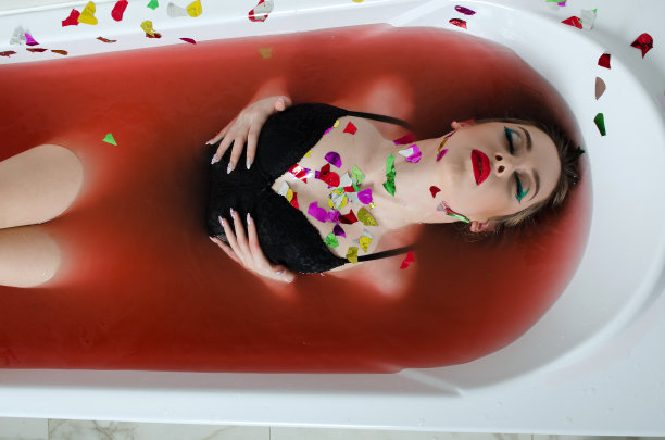 女孩带着明亮的妆容在用红色的水洗澡图片下载