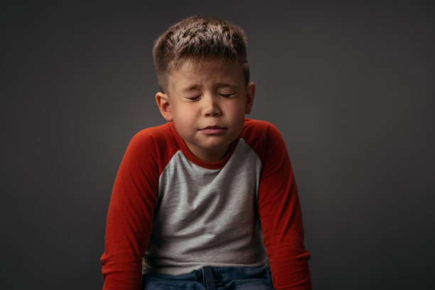 许个愿穿着红白衬衫的小男孩闭着眼睛坐在椅子上。为圣诞节许愿的概念。面部表情，情绪，感觉图片下载