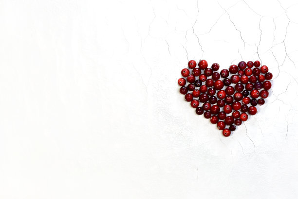 心脏的形状是内衬沼泽红蔓越莓浆果。白色背景上有裂缝和粗糙的纹理。图片下载