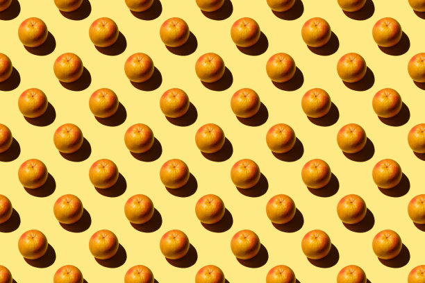 时尚的图案与新鲜的水果在明亮的淡黄色的背景。以彩色纸为背景的简约风格。彩色照片。平的。最小的创意概念。食品的背景。切片葡萄柚图片下载