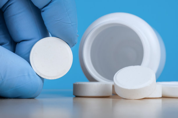 手里拿着医用手套，旁边是装着药片的空瓶子。图片下载