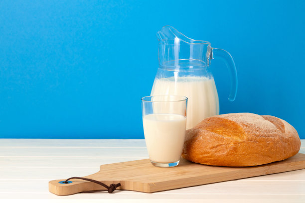 木桌上放着一杯牛奶和一条面包图片下载