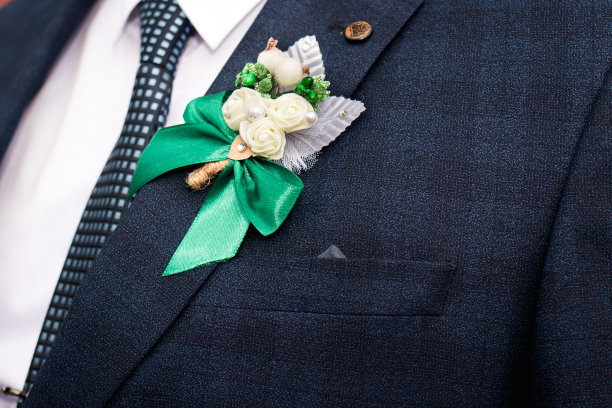 在新郎婚礼当天，在蓝夹克上佩戴美丽的玫瑰胸花。图片下载
