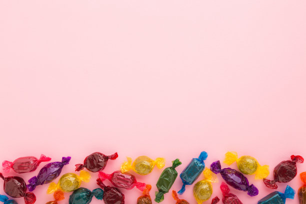 彩色包装的巧克力糖果在浅粉色的桌子背景。柔和的颜色。特写镜头。文本的空位置。自顶向下的观点。图片下载