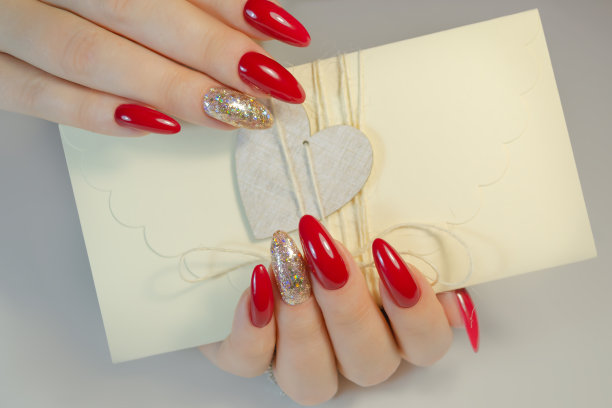 一位年轻女子的手拿着一个礼品信封。修指甲。图片下载