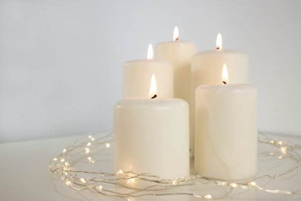 白色背景上燃烧着的大蜡烛和圣诞花环。侧视图，文本空间。图片下载