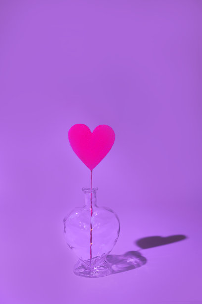 在一个透明的酒瓶里，紫色的卡片上有一个红色的心，背景上有一个坚硬的阴影。图片下载