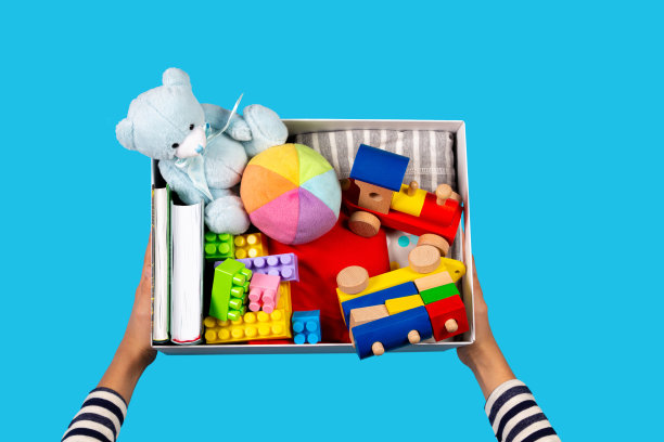 捐赠的概念。孩子的手与捐赠箱，衣服，书籍和玩具在浅蓝色的背景。俯视图图片下载