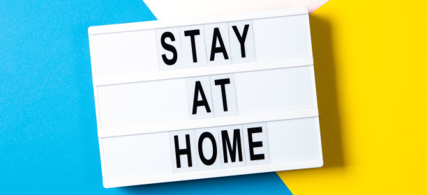 白色灯箱文字呆在家里黄色，粉色和浅蓝色背景。保健、医疗、检疫理念。俯视图图片下载