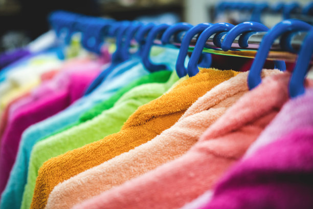 多色毛巾布长袍挂在衣架上。在商店或市场上出售的服装的创意展示。图片下载