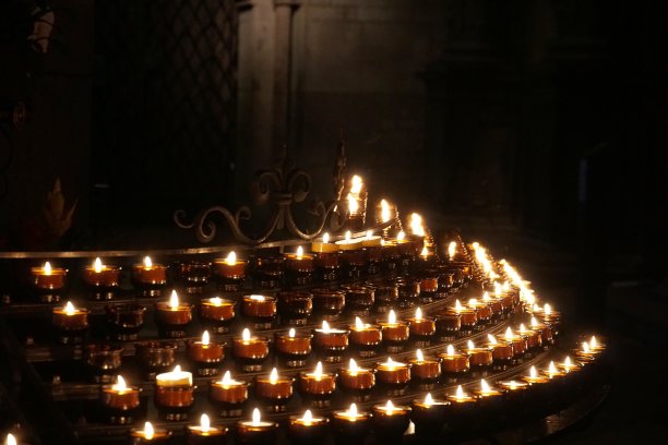 在罗马天主教堂里，信徒或游客点燃的小蜡烛放在玻璃支架上燃烧。它们排成一行，形成一个半圆形，照亮了教堂的内部。图片下载