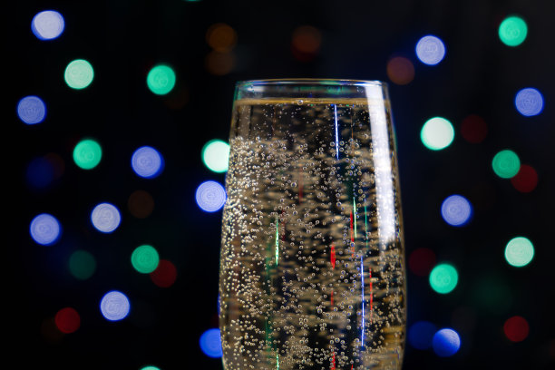 用香槟庆祝圣诞节和新年。香槟杯与彩色的点背景。图片下载