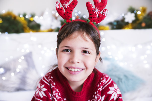 快乐的小女孩在为圣诞节装饰的房间里。那孩子在近处微笑。在家庆祝新年。副本的空间。高质量的照片图片下载