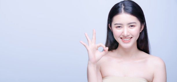 美丽的肖像欢快迷人的半裸亚洲女人与微笑的脸显示ok手势标志和展望在相机孤立明亮的蓝色背景。富有表现力的面部表情。图片下载