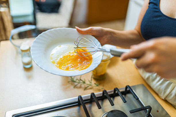 女厨师在盘子里搅拌鸡蛋的特写照片。图片下载