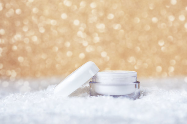 化妆霜在白色的罐子，用于脸部和手部皮肤护理。金色的焦外成像背景。冬季护肤概念图片下载