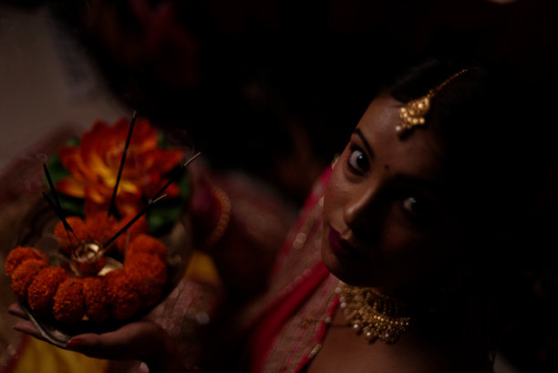 在排灯节的晚上，一个印度孟加拉美丽的黑发女人在彩色的背景前崇拜的肖像。图片下载
