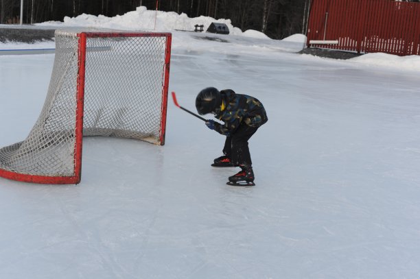 一名年轻的冰球业余选手在冰场上用一根棒子打冰球图片下载