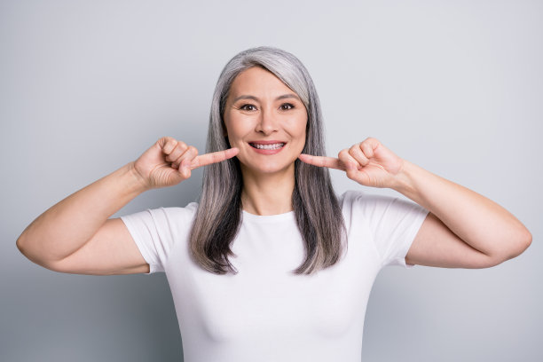 照片滑稽可爱的高级女士穿休闲装指着手指脸颊孤立的灰色背景图片下载