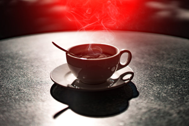 木桌上放着一杯咖啡。用大杯子盛热饮。黑暗的背景。特写镜头。图片下载