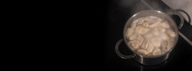 横幅上写着煮饺子和肉在锅里，在黑色的背景与文本复制空间，细节，特写图片下载