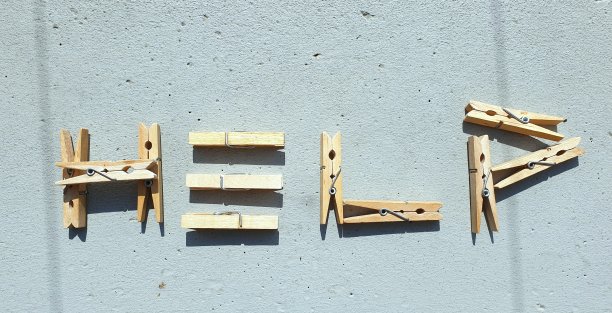 用镊子写的“帮助”字，孤立在灰色的石头背景上。不求他人帮助的概念。图片下载