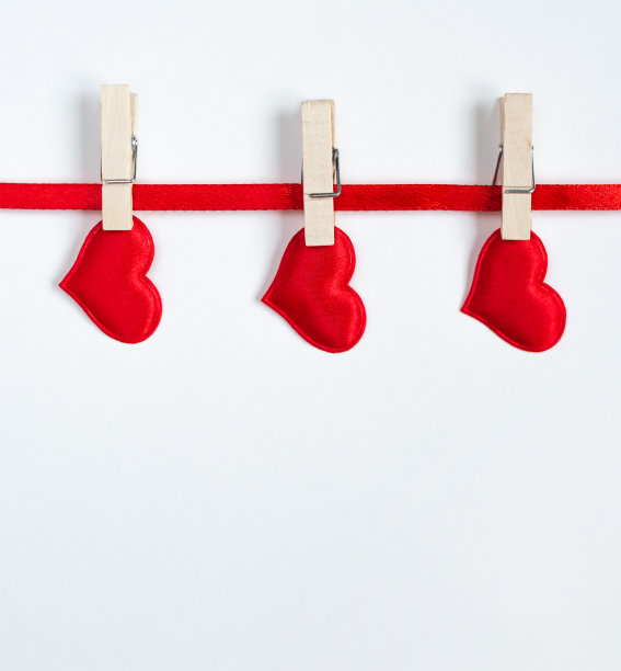 红丝带上挂着三颗红心，上面留有复制空间。情人节的概念图片下载