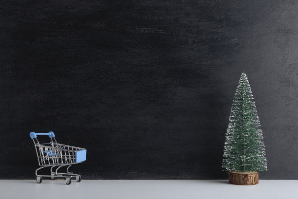 购物车和微型圣诞树在黑色的背景。新年购物。本空间图片下载