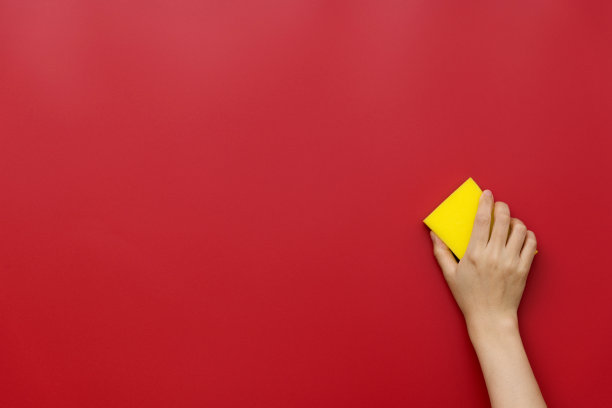 女人用海绵擦拭红色的墙壁图片下载