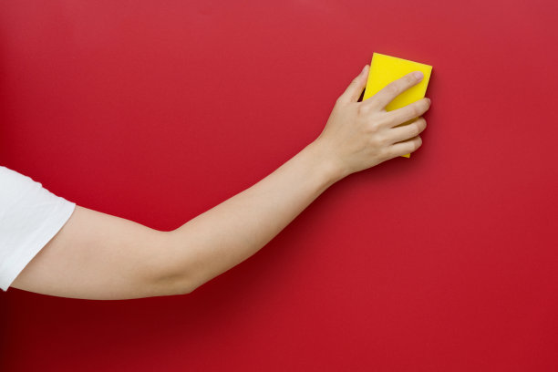 女人用海绵擦拭红色的墙壁图片下载