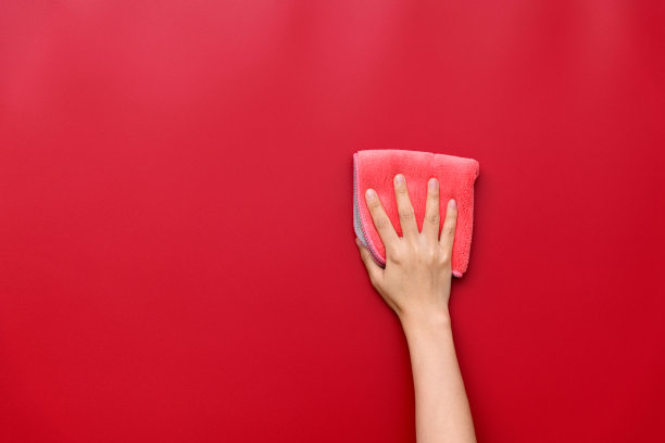 女人用抹布擦着红墙图片下载