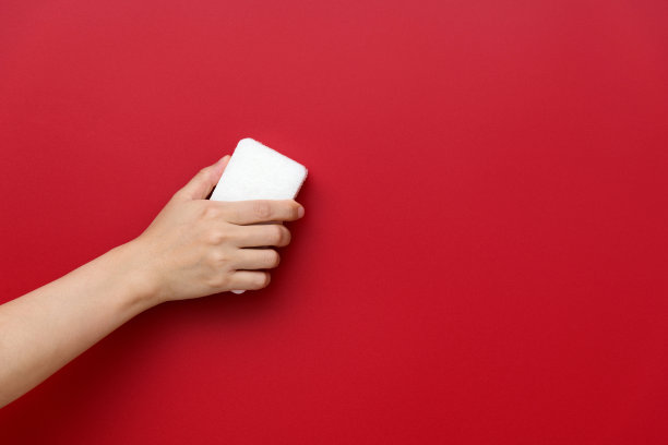 女人用海绵擦拭红色的墙壁图片下载