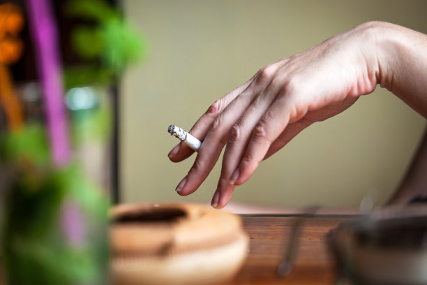 一个女人手拿香烟在酒吧里图片下载