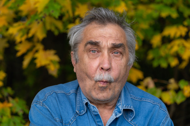 70岁老人的肖像，手势滑稽可笑，他的表情看起来很愉快。图片下载