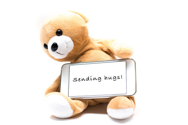 发送拥抱:泰迪熊抱着智能手机短信图片下载