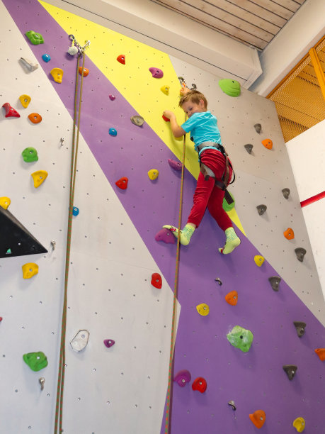 一个小男孩正在攀岩墙上用绳子攀爬图片下载