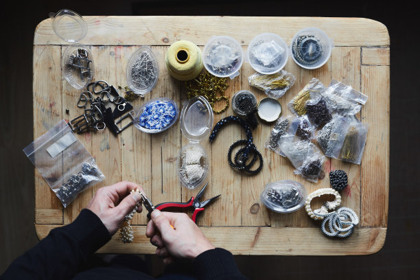 男子手工制作的手工首饰，配件在木制背景上图片下载