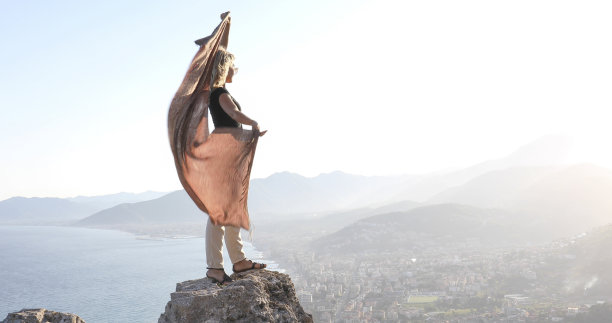 年轻女子清晨在海边的悬崖上跳舞图片下载