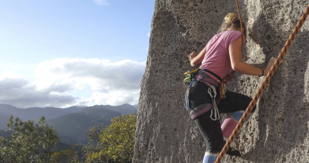 年轻女子攀登陡峭的岩壁图片下载