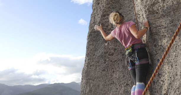 年轻女子攀登陡峭的岩壁图片下载
