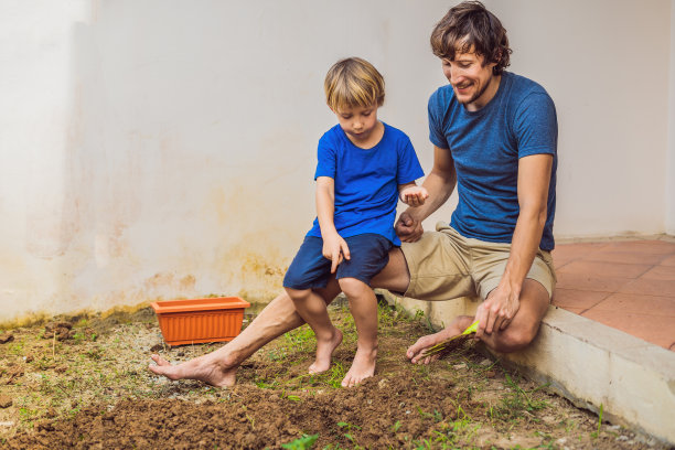 父亲和儿子在房子附近的花园里种花图片下载