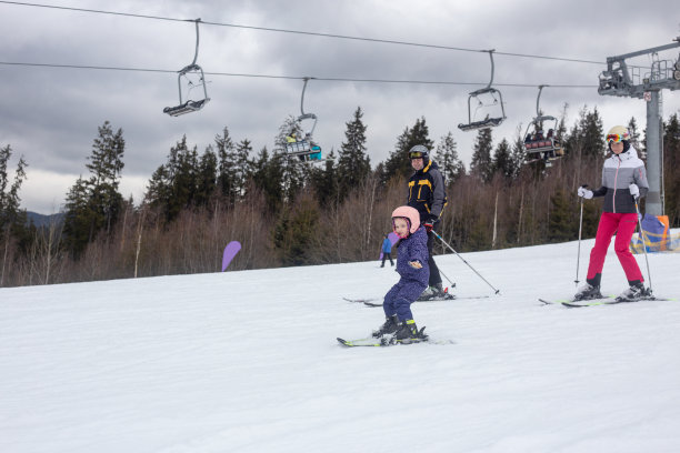 一个带着一个孩子的家庭正在滑雪场滑雪。图片下载