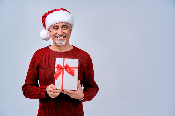 微笑的大胡子成熟男子摆姿势与礼盒图片下载