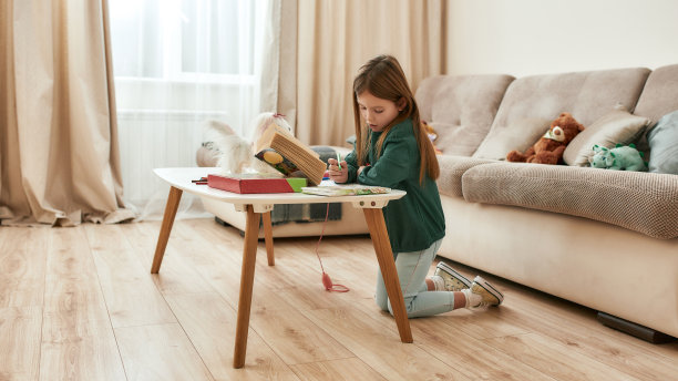 一个小女孩独自坐在家里的桌子旁看书，在她的日记中做笔记图片下载