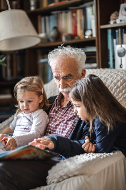 可爱的小女孩和爷爷一起读儿童读物图片下载