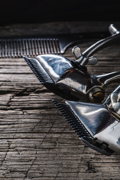 旧的木头表面上放着旧的理发工具。两把老式手持式理发钳和梳子。垂直图片下载